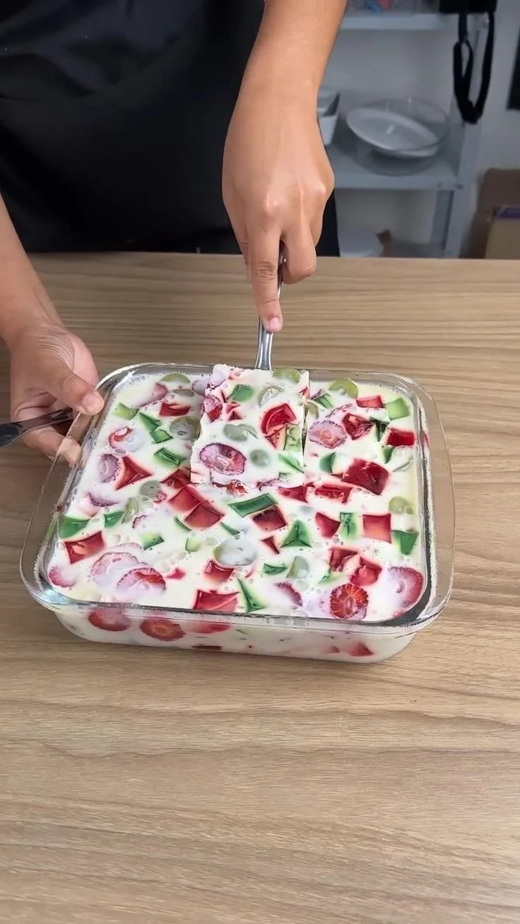 Colorful layered fruit gelatin dessert served in a glass dish.